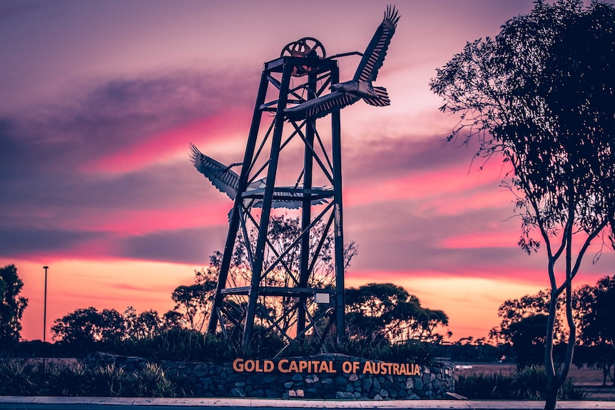 A photograph of a sign at Kalgoorlie-Boulder Airport taken at sunset claiming the city as Australia's gold capital. 